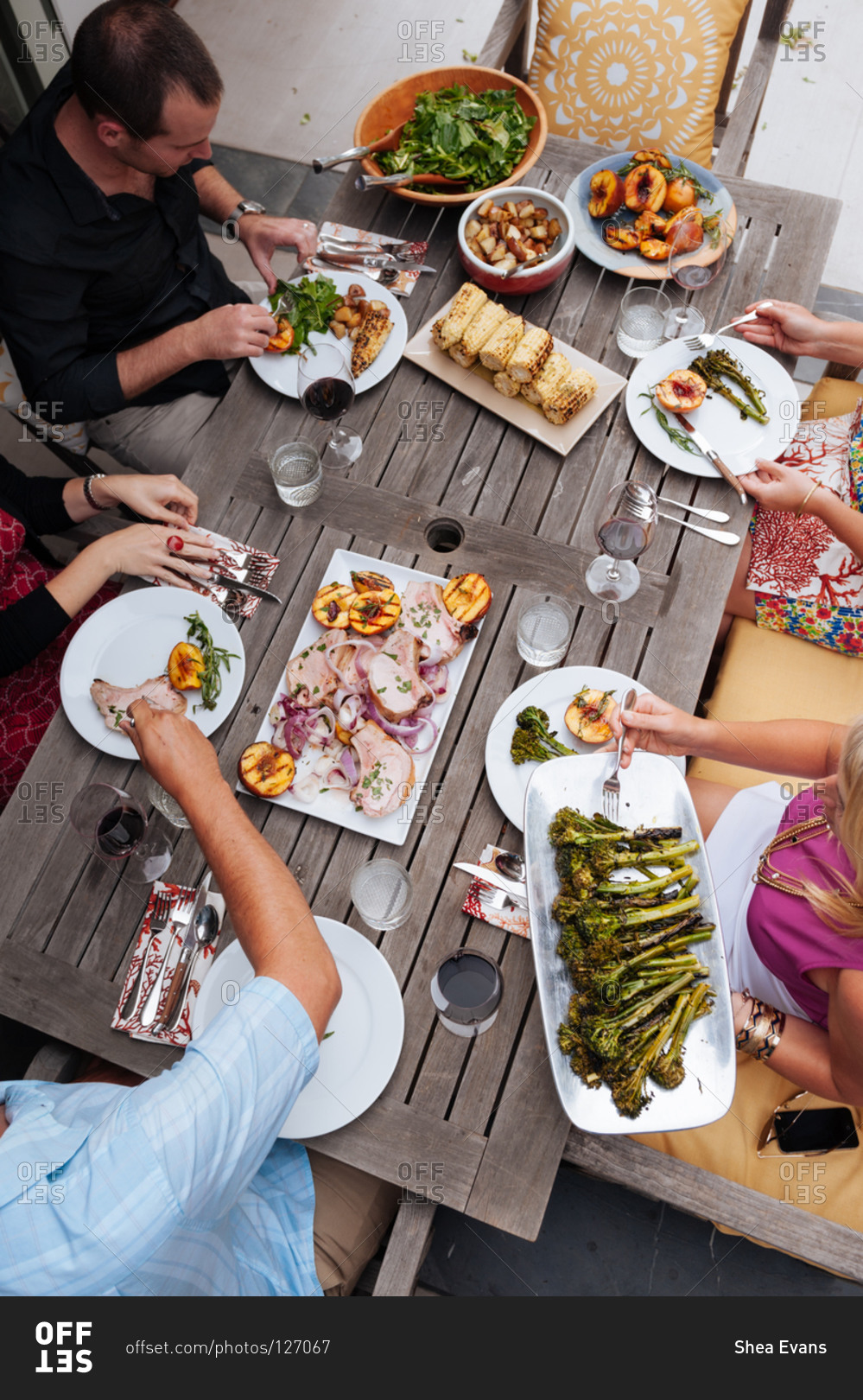Overhead view of friends enjoying a meal at a summer table on their patio prepared by a personal chef