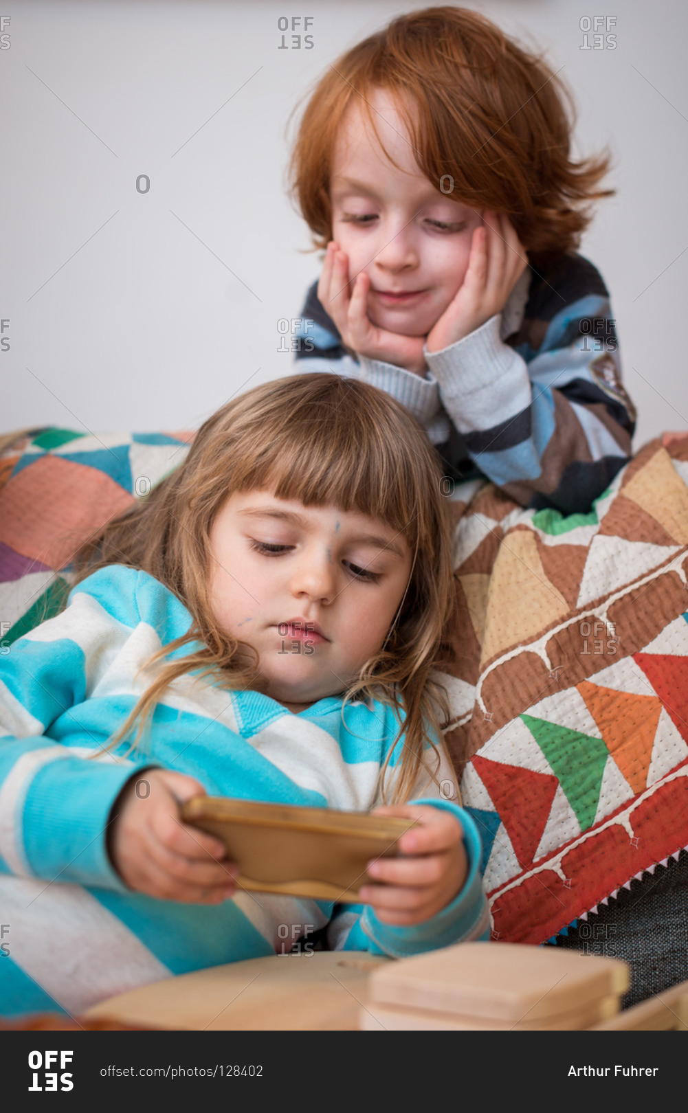 Girl playing on smartphone while a boy watching it