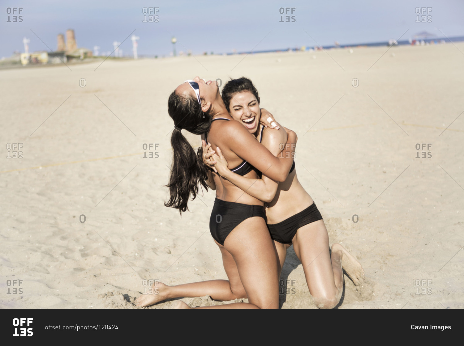 Two young women cheering at beach volleyball court