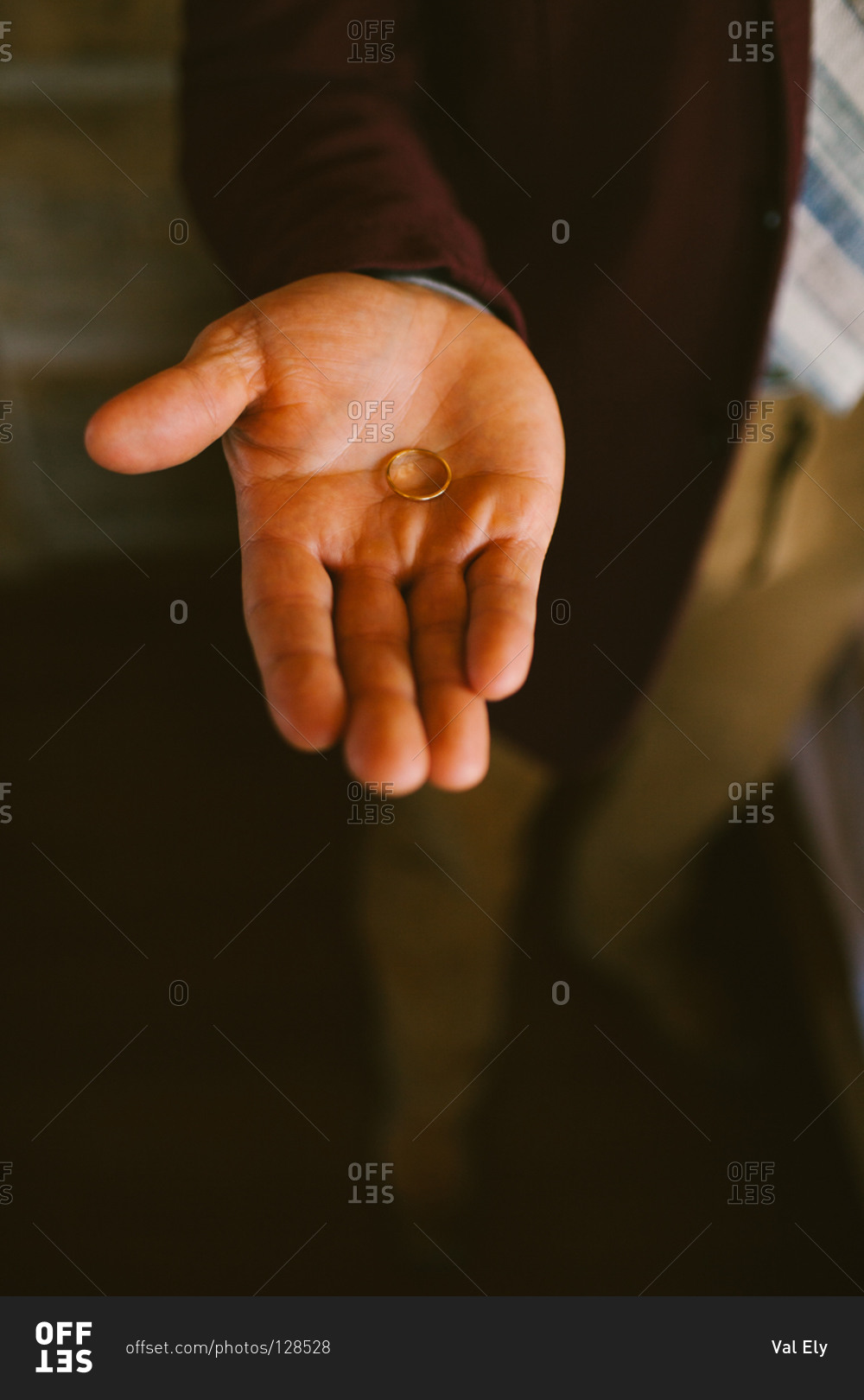 Man holding wedding ring on his palm stock photo - OFFSET