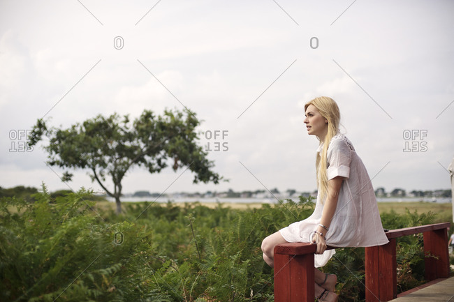 Side view of blonde girl sitting on railing