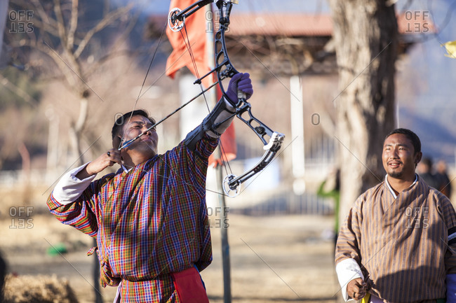 Paro, Bhutan - February 3, 2011: Man shooting an arrow at an archery competition in Paro, Bhutan