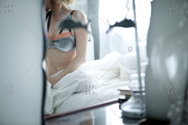 Woman wearing a bra lying on a bed stock photo - OFFSET