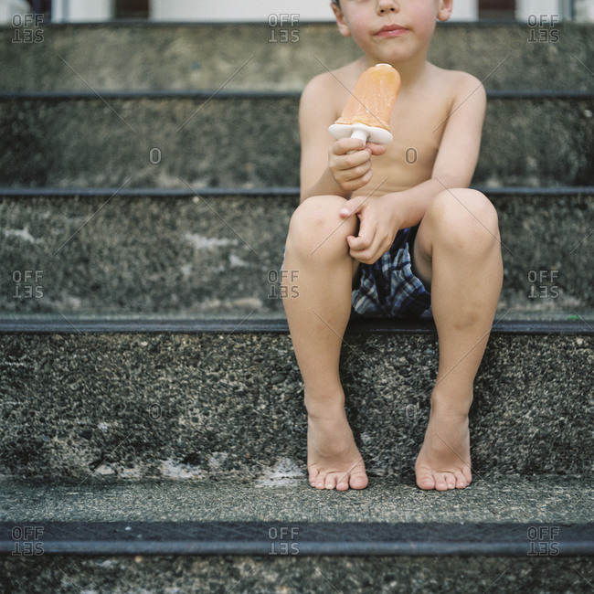 Child eating ice lolly on staircase