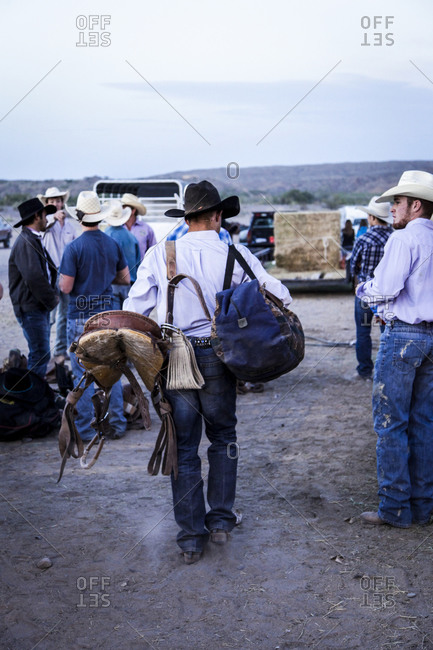 New Mexico, USA - May 11, 2013: Cowboy carries saddle and bag after rodeo in Truth or Consequences, New Mexico, USA
