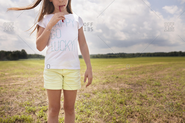 Girl eating twizzler in open field