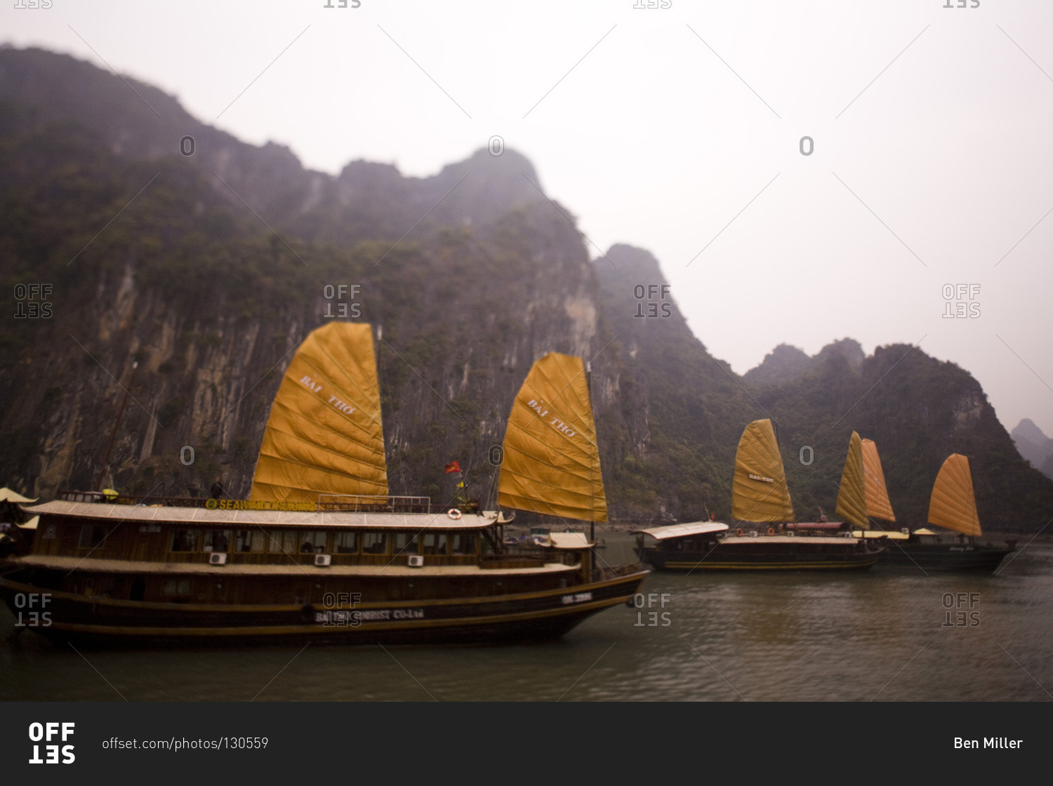 Sail boats in front of large limestone formation, Halong Bay, Vietnam