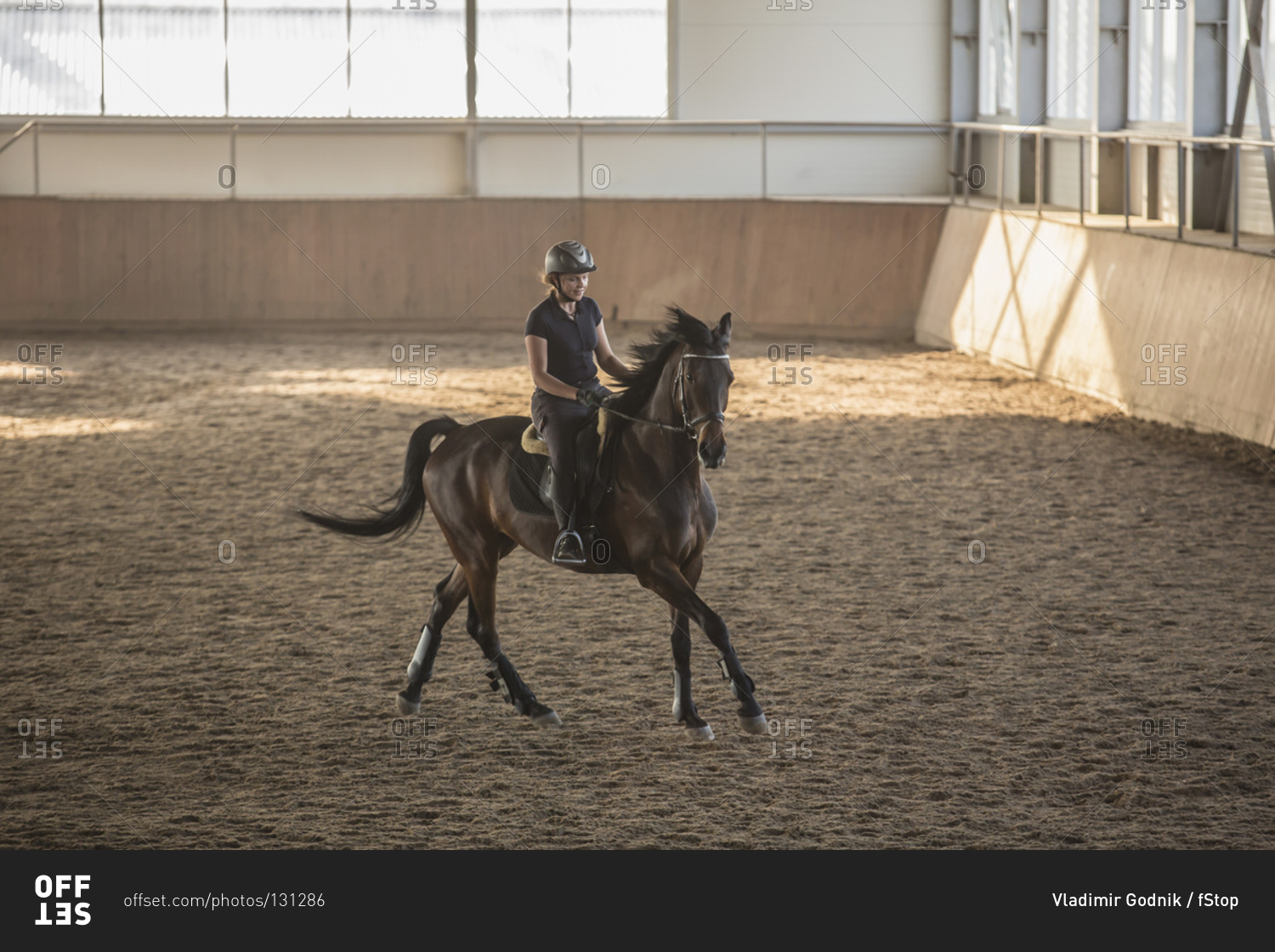 Woman riding horse in training stable