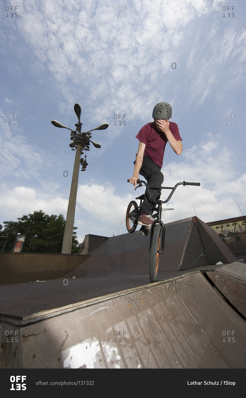 A young man balancing on a BMX bike at the top of a ramp