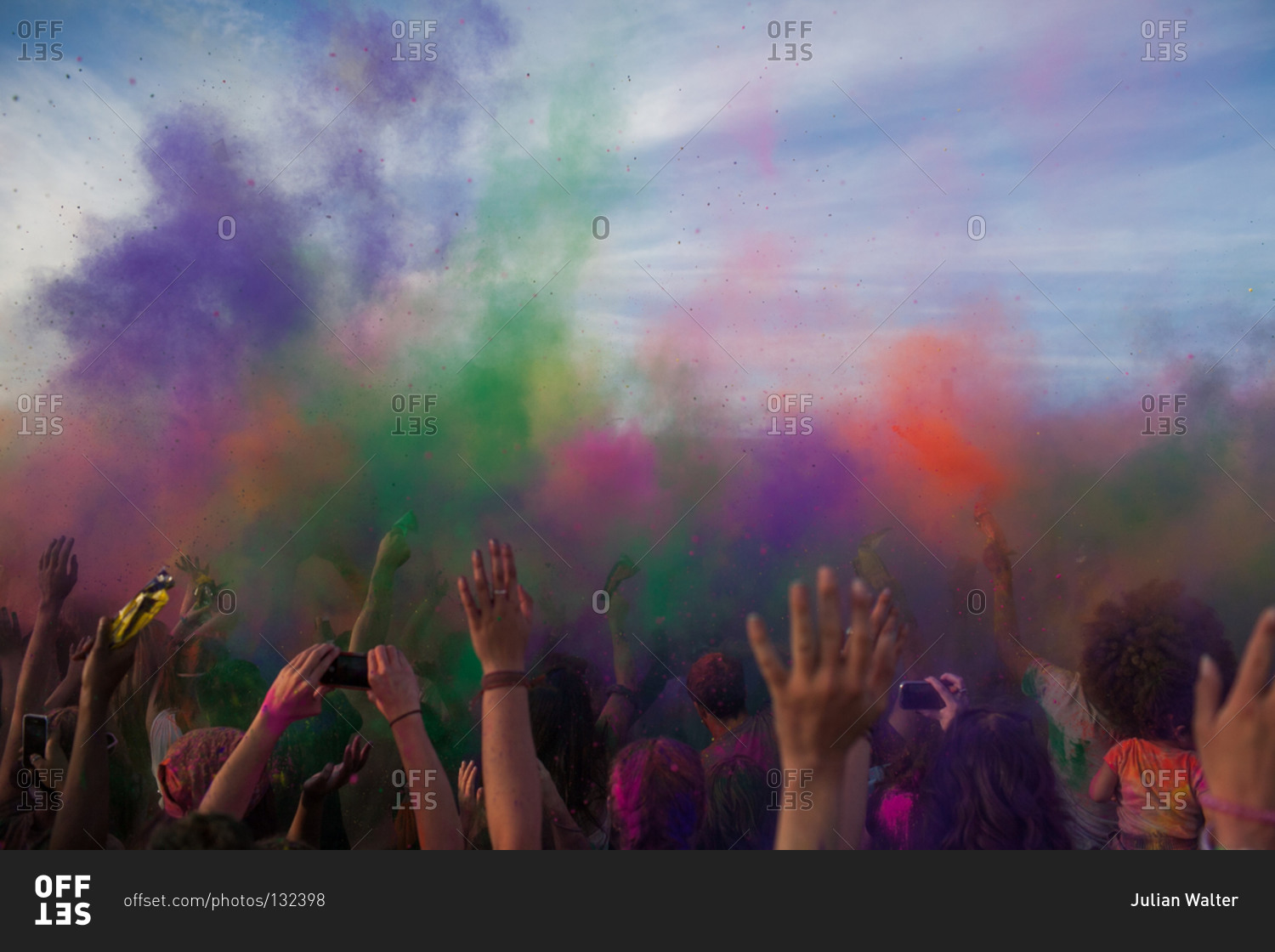 Crowd throwing bright colored powder paint in the air at Holi Fe