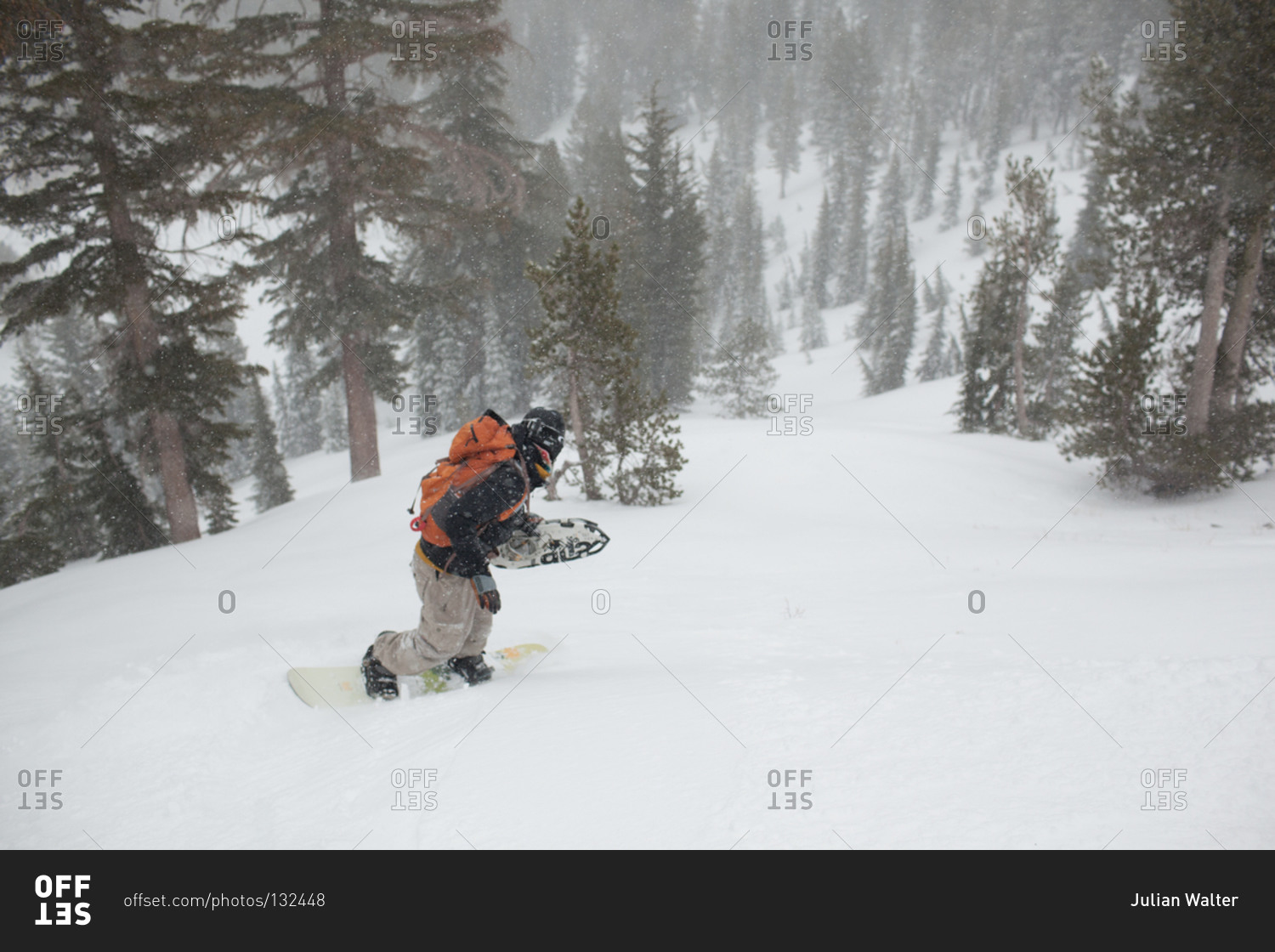 Man snowboarding down wooded hill near Lake Tahoe, California
