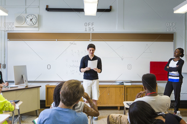 Teenage boy giving a presentation in a school stock photo - OFFSET