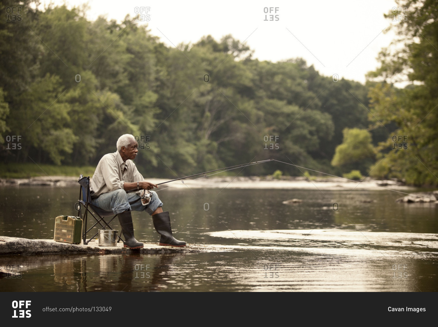 Relaxed man fishing from river shore