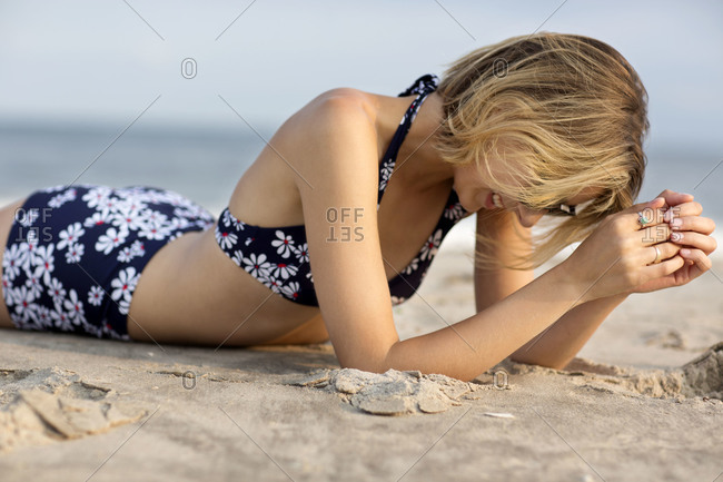 Beautiful young woman wearing bikini lying on beach stock photo - OFFSET