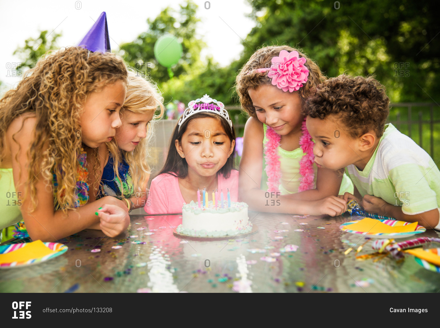 Children blowing out the candles on birthday cake together