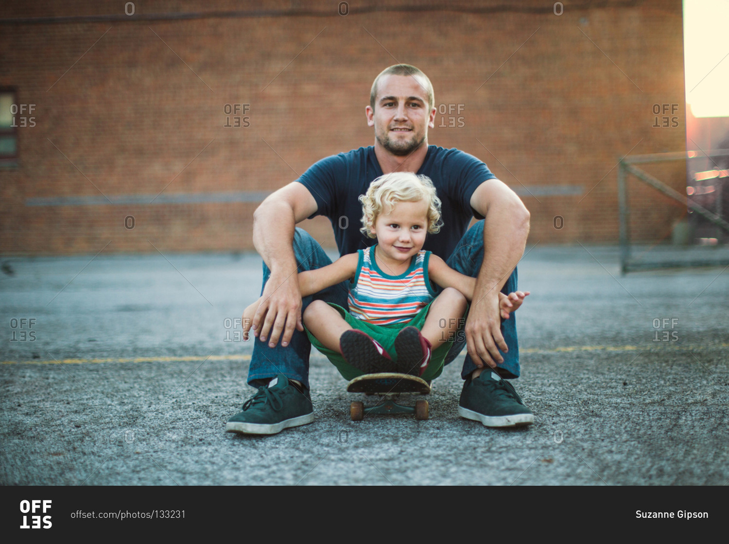 Young man sitting with boy on a skateboard