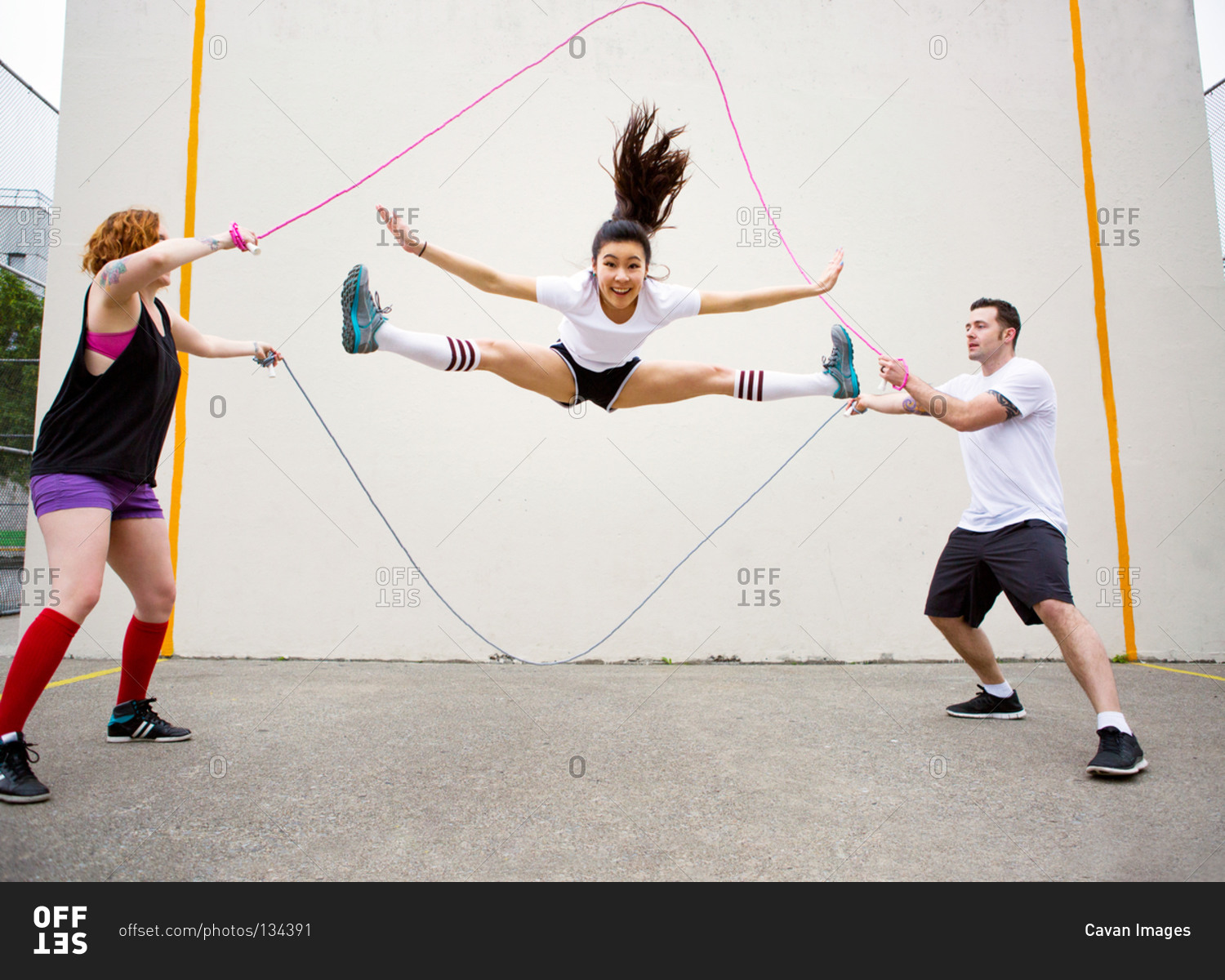 Young adults skipping rope in the park stock photo - OFFSET