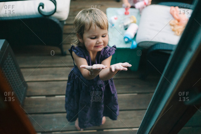 High angle view of toddler girl showing her messy hands