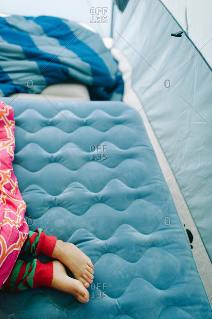 Low section view of kid sleeping on inflatable mattress