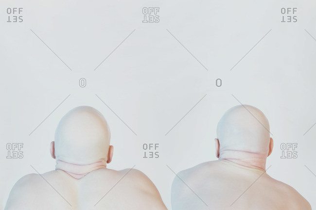 Back view of two bald men in front of white background