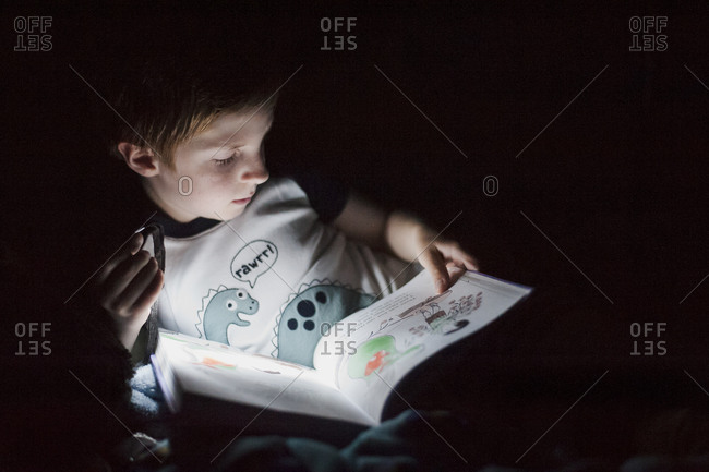 Boy reading by the light of a flashlight