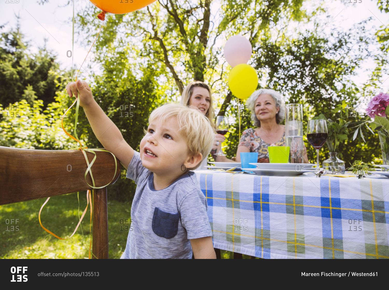 Boy at table with family of three generations in garden