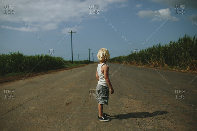 Boy standing on a rural road stock photo - OFFSET