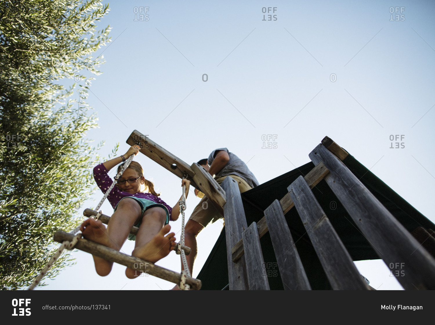 Young girl climbing on a rope ladder stock photo OFFSET