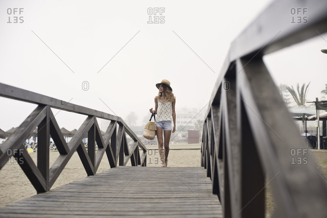 Woman walking on wooden bridge by the beach