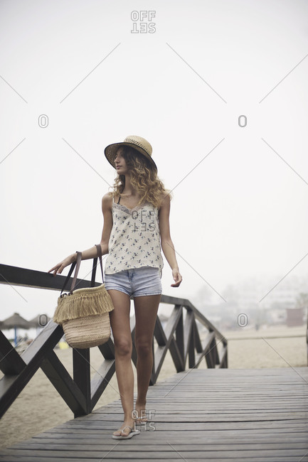 Woman walking on wooden bridge by the beach