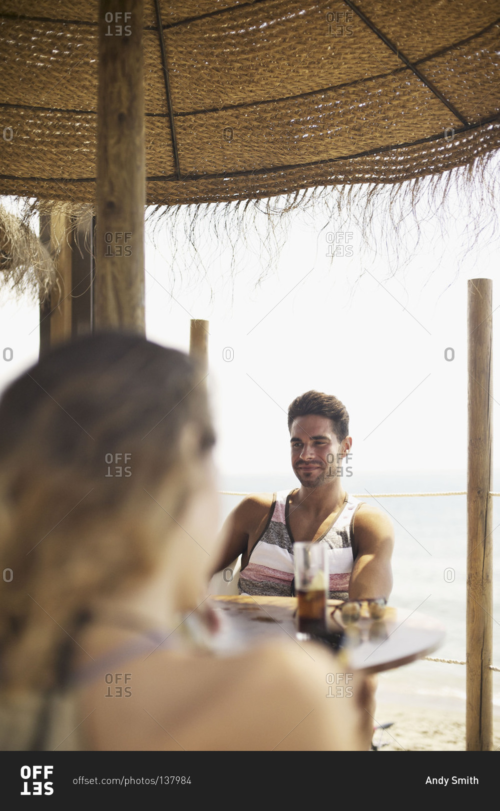 Man seen over woman's shoulder in bar of tropical resort