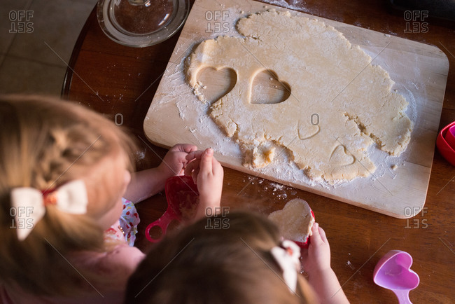 Little girls making heart-shaped cookies on Valentine\'s Day