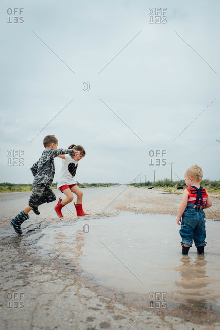 Children jumping in a puddle stock photo - OFFSET