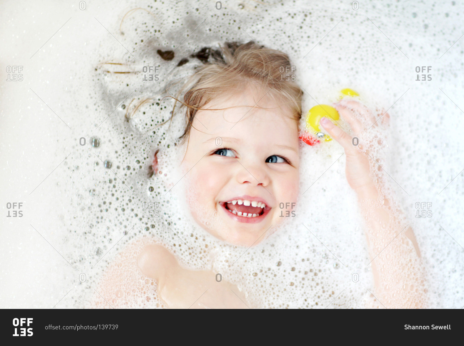 Top view of little girl with a rubber duck in the bathtub
