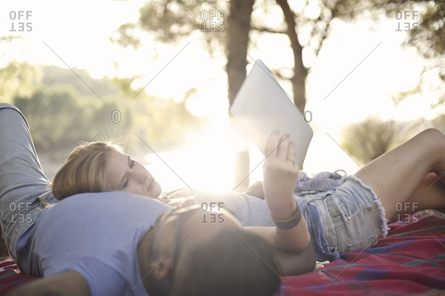 Couple lying out by a lake in the woods