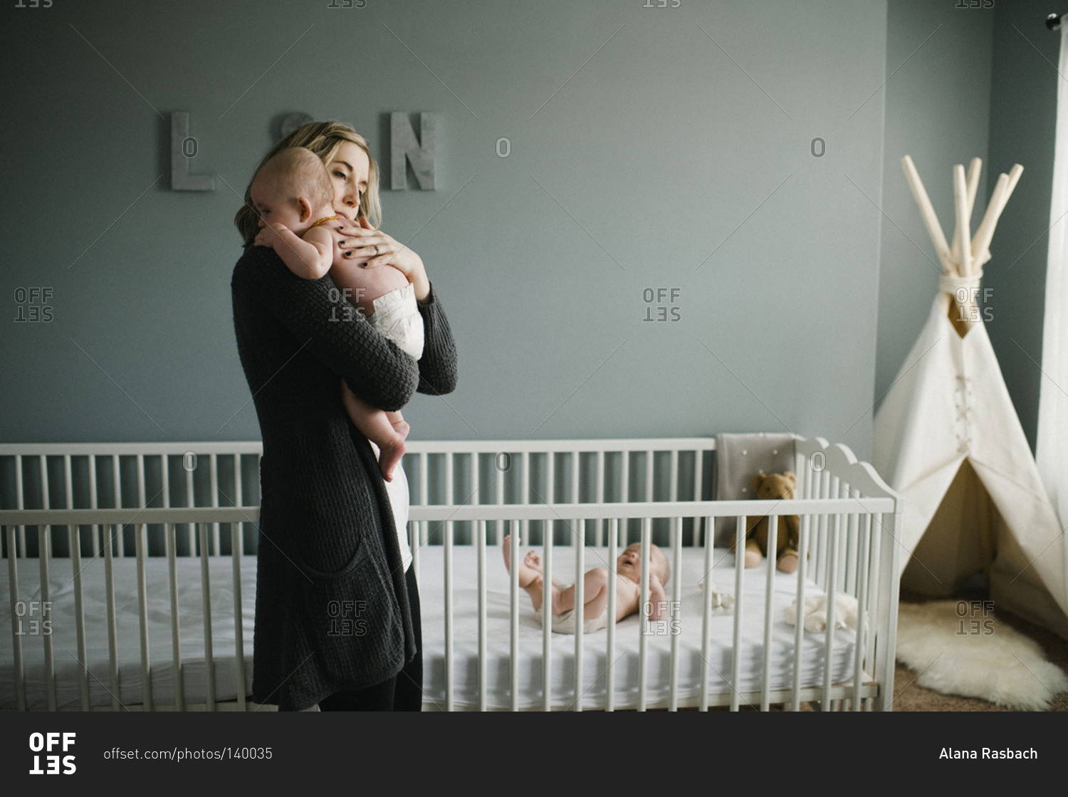 Woman holding her son next to a crib