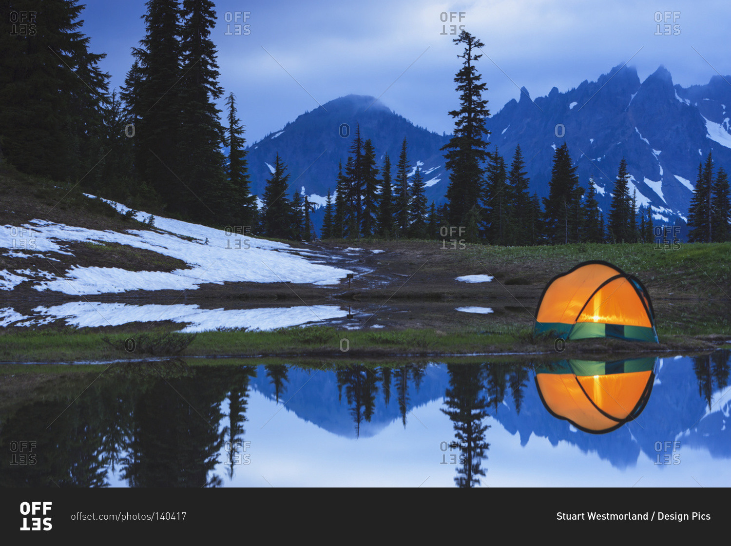 Camping tent at sunset by a small reflecting pond