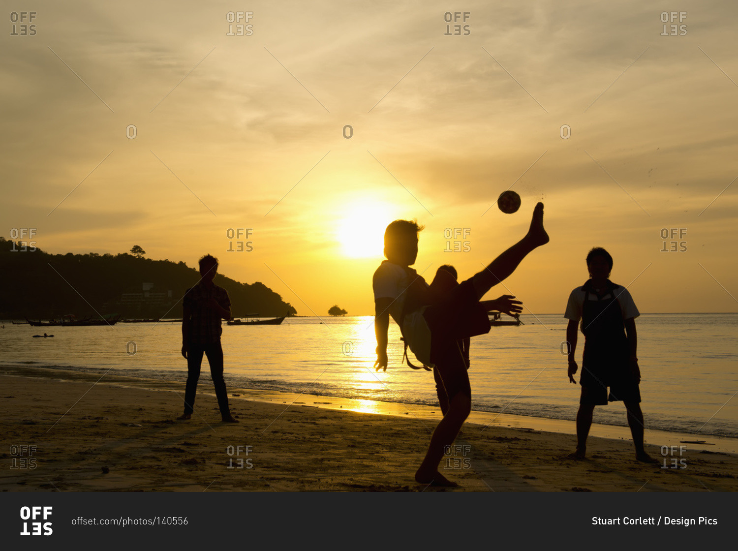 Men playing takraw ball at sunset on the beach
