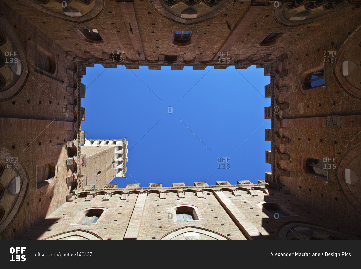 Low angle view up the walls of a building to a blue sky, Siena, Italy