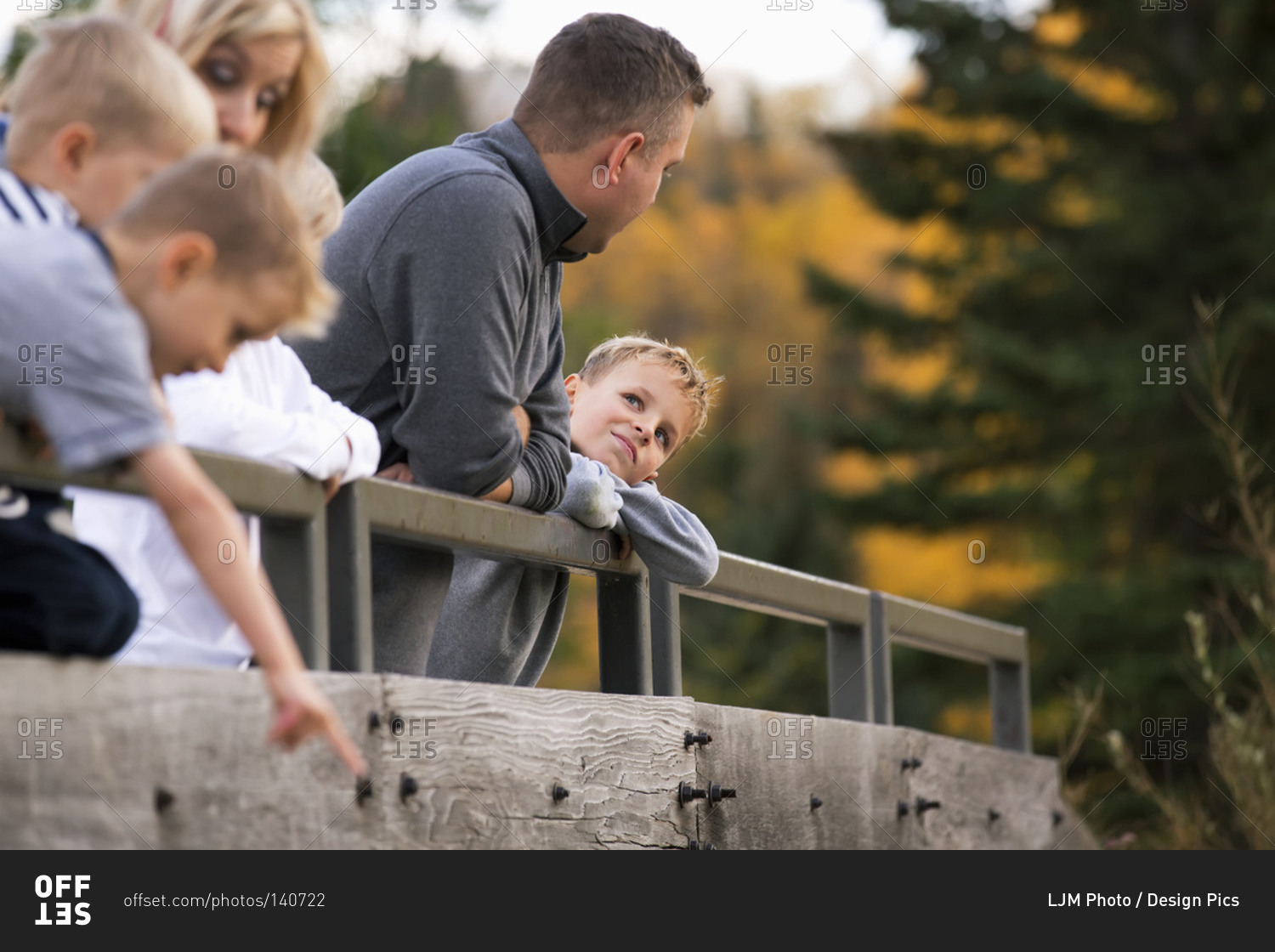 Young family on a bridge in a park in autumn