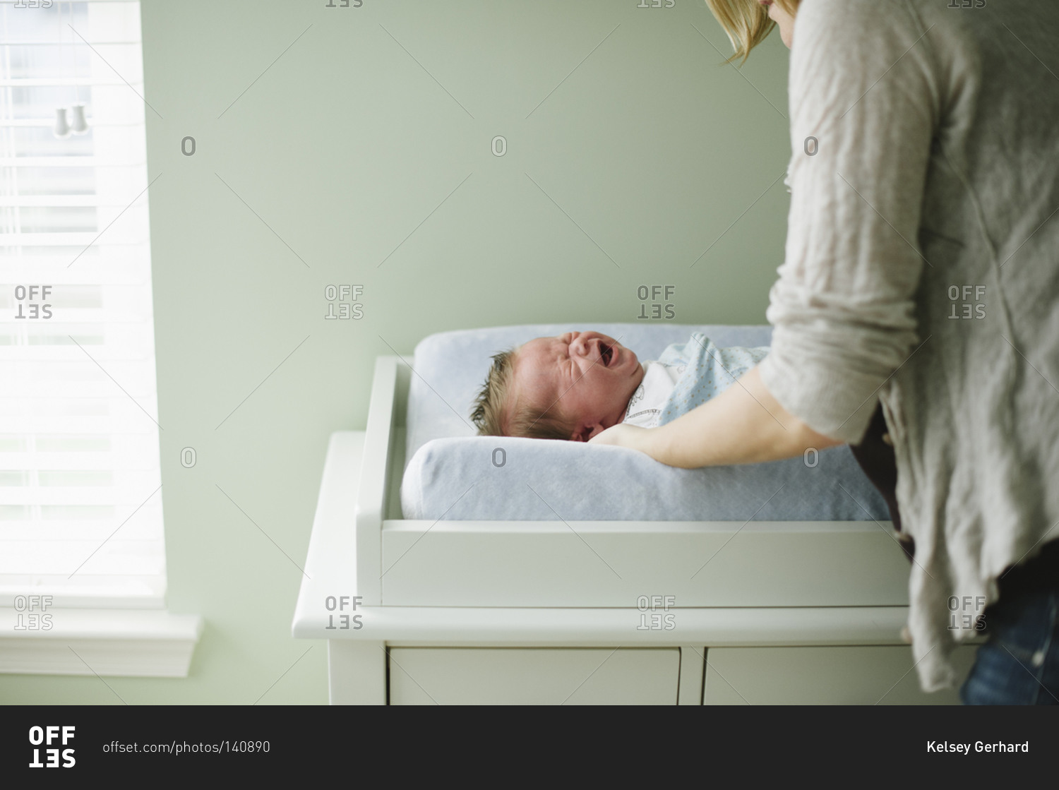 A baby cries on a changing table stock photo OFFSET