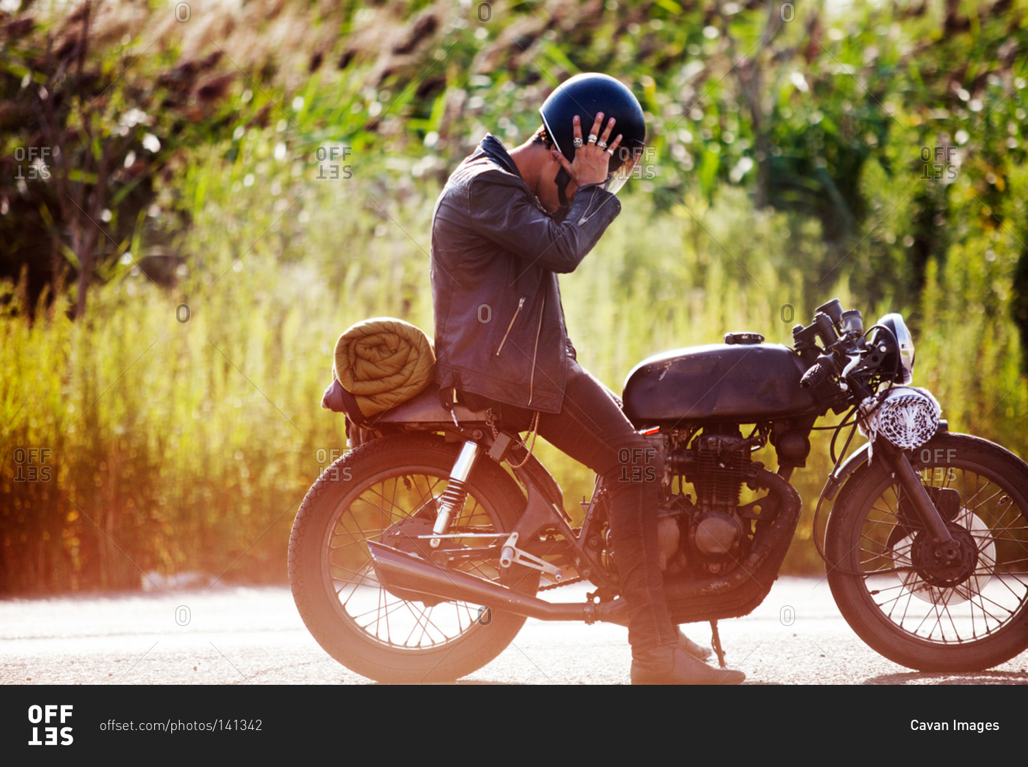 Man taking off his helmet on a motorcycle stock photo - OFFSET