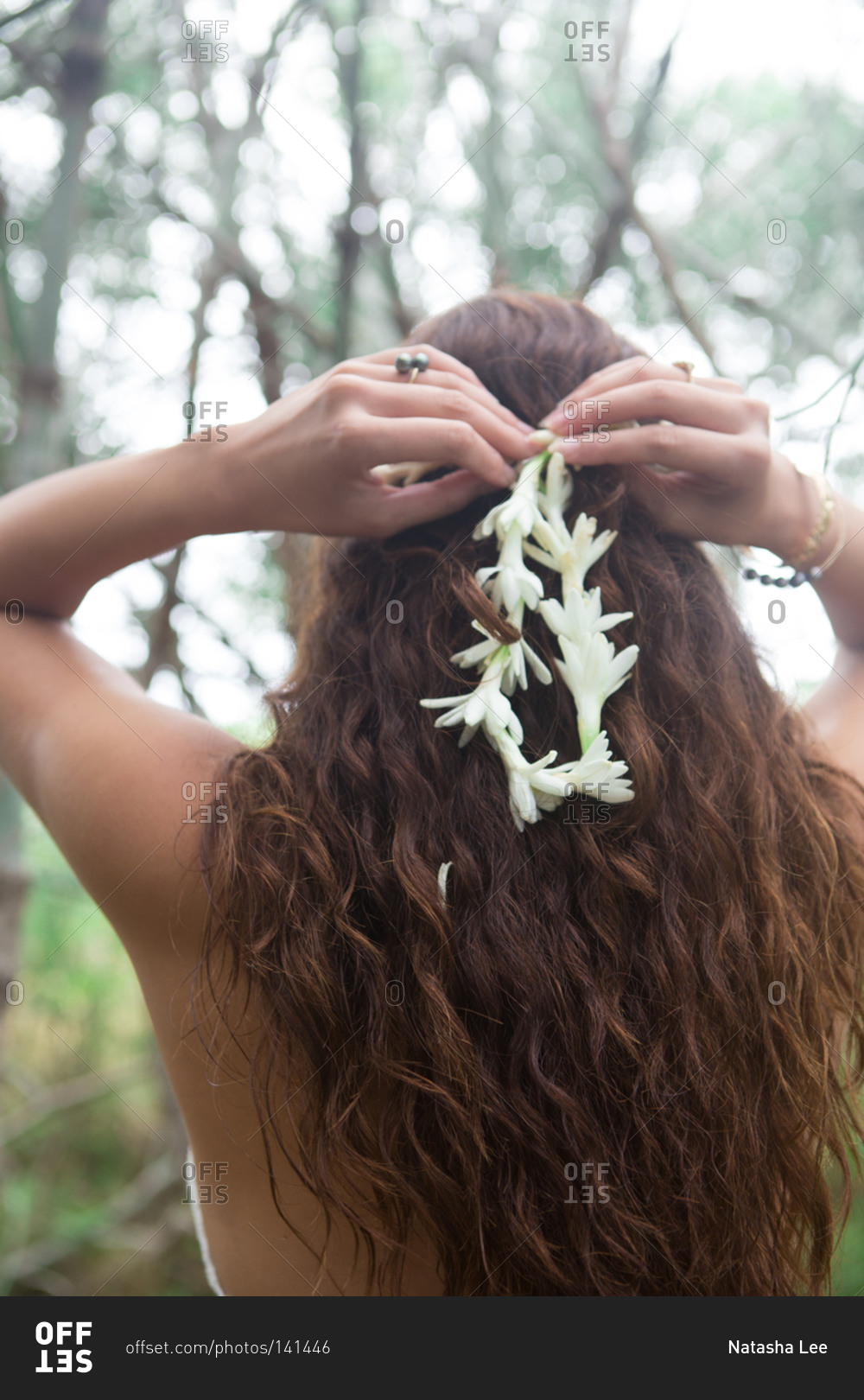 Woman putting white flowers in her hair