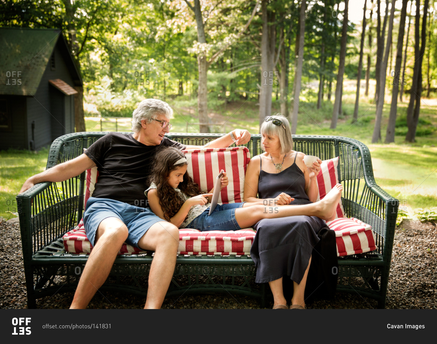 Elderly couple resting with their granddaughter on an outdoor couch
