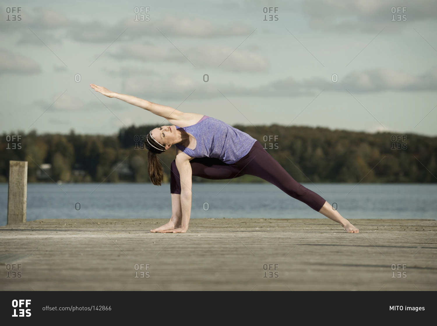 Woman practicing yoga on jetty, Woerthsee, Bavaria, Germany