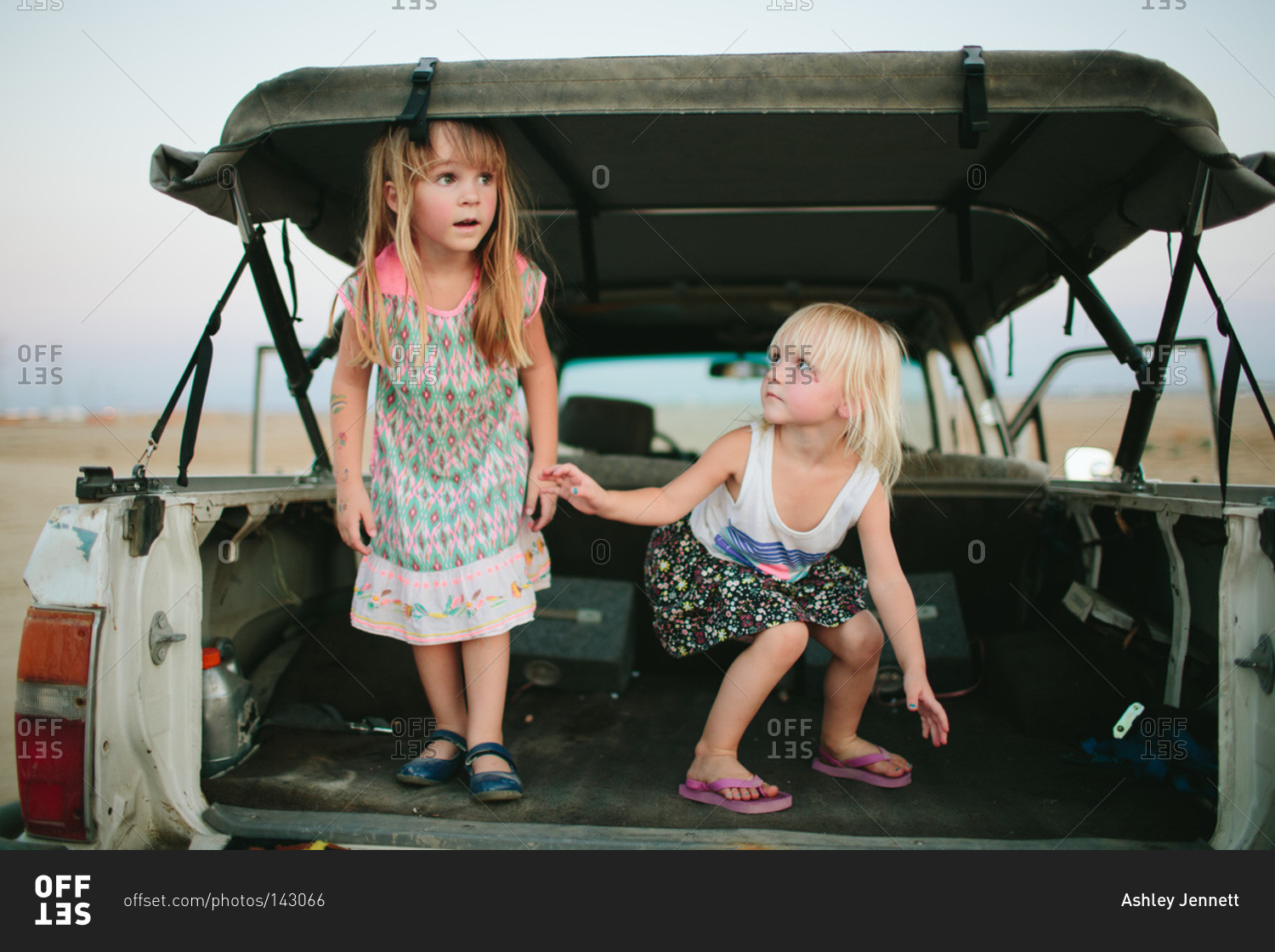 Two girls play in a truck bed