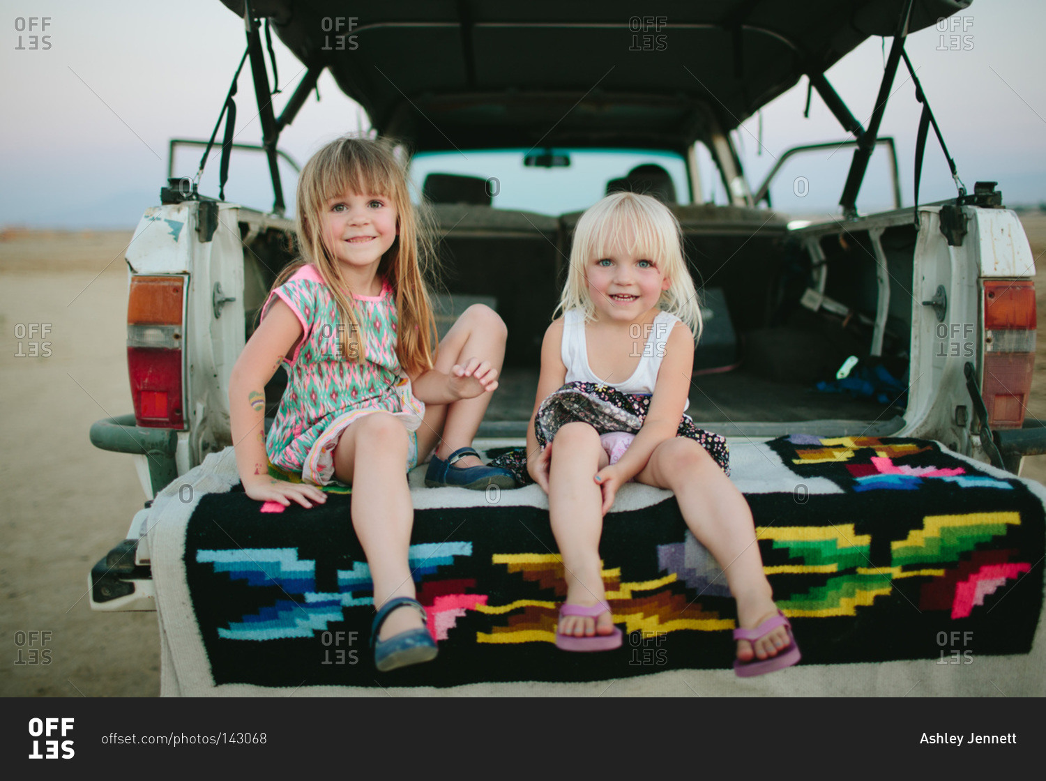 Two girls sit on the bed of a truck