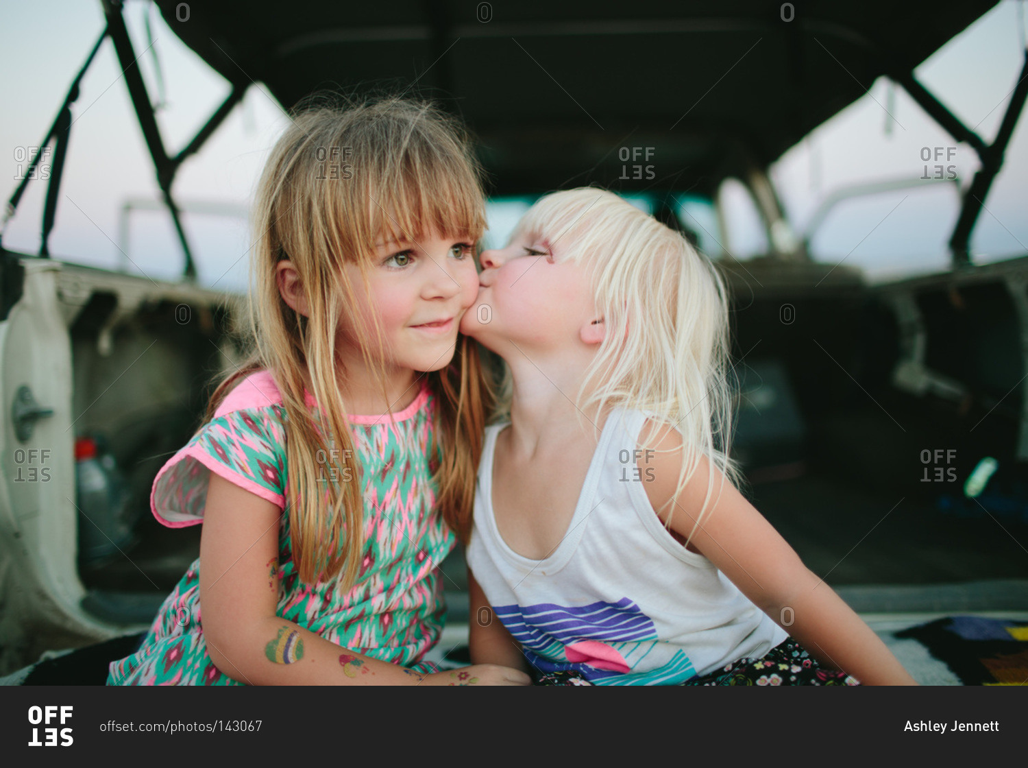 A girl kisses another girl by a truck