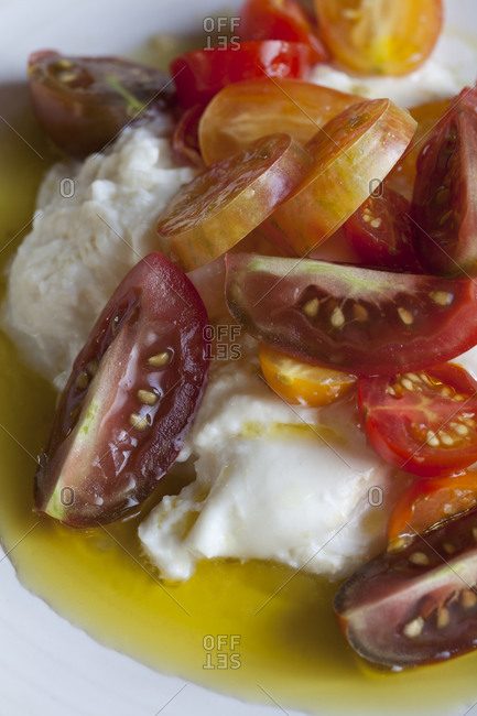Burrata and cherry tomatoes sit in olive oil