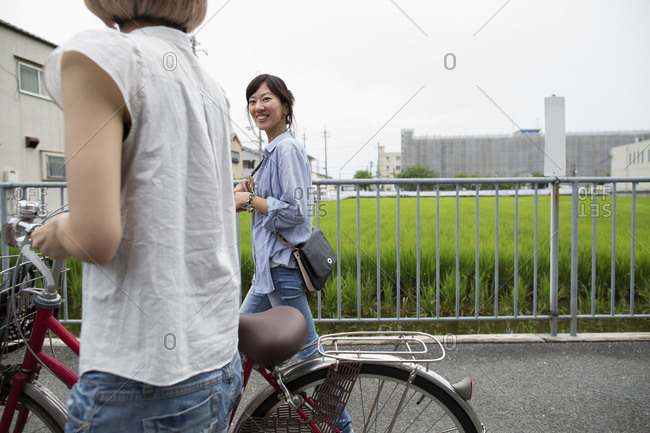 Two women walking along a footpath, pushing a bicycle